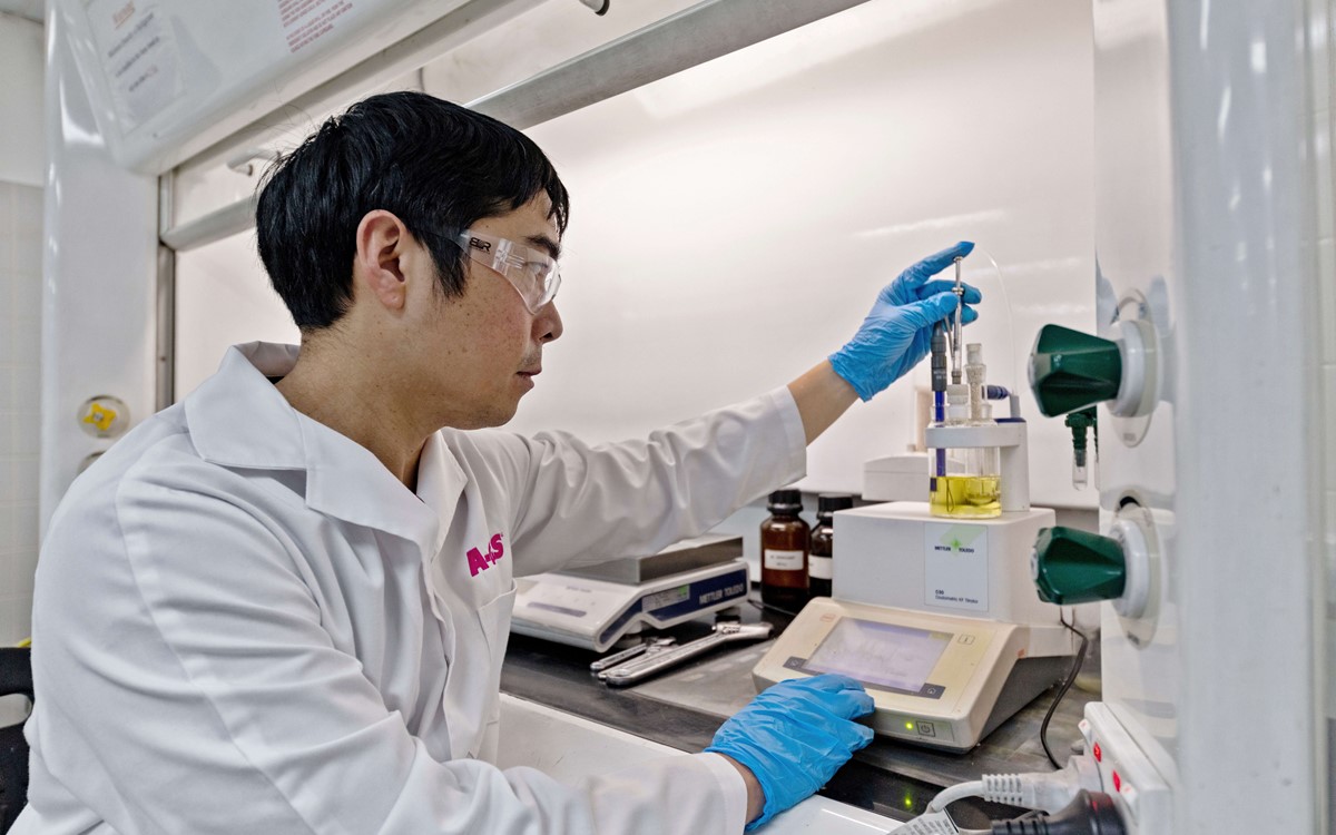 Technician in a white coat working with laboratory equipment
