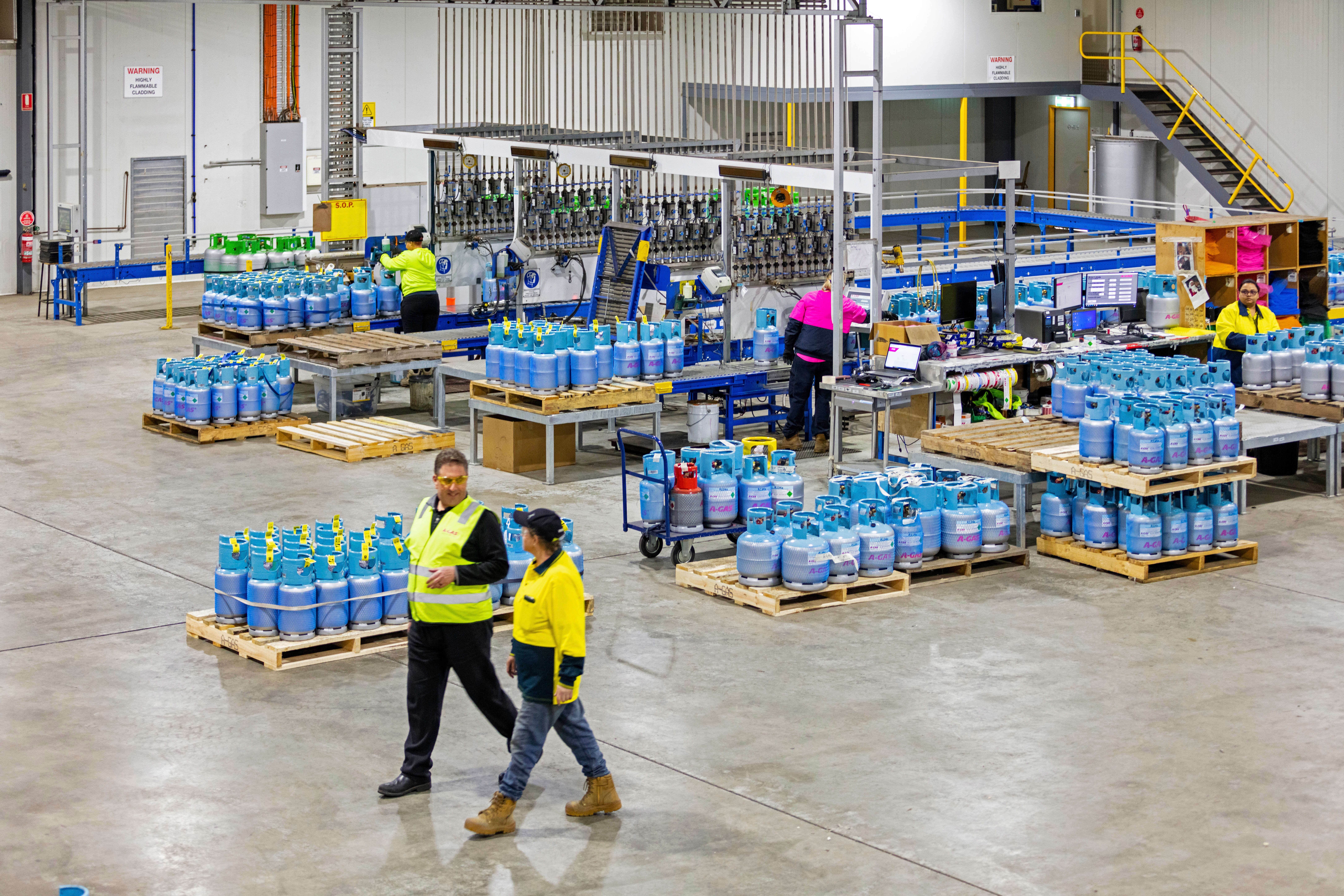 A man and woman talking while walking through a warehouse full of cylinders 