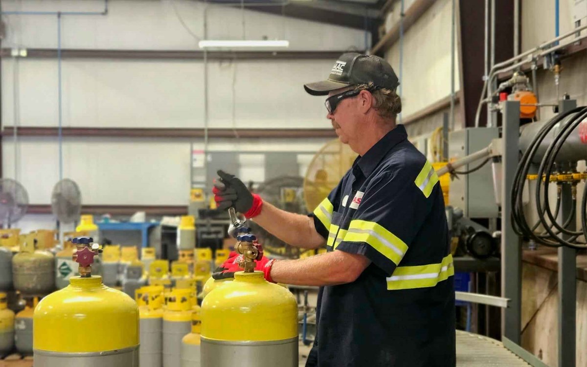 A man working with two yellow and silver cylinders