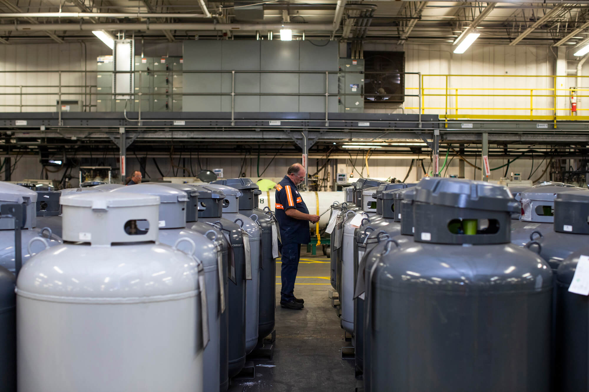 A person stood in between two rows of industrial gas cylinders
