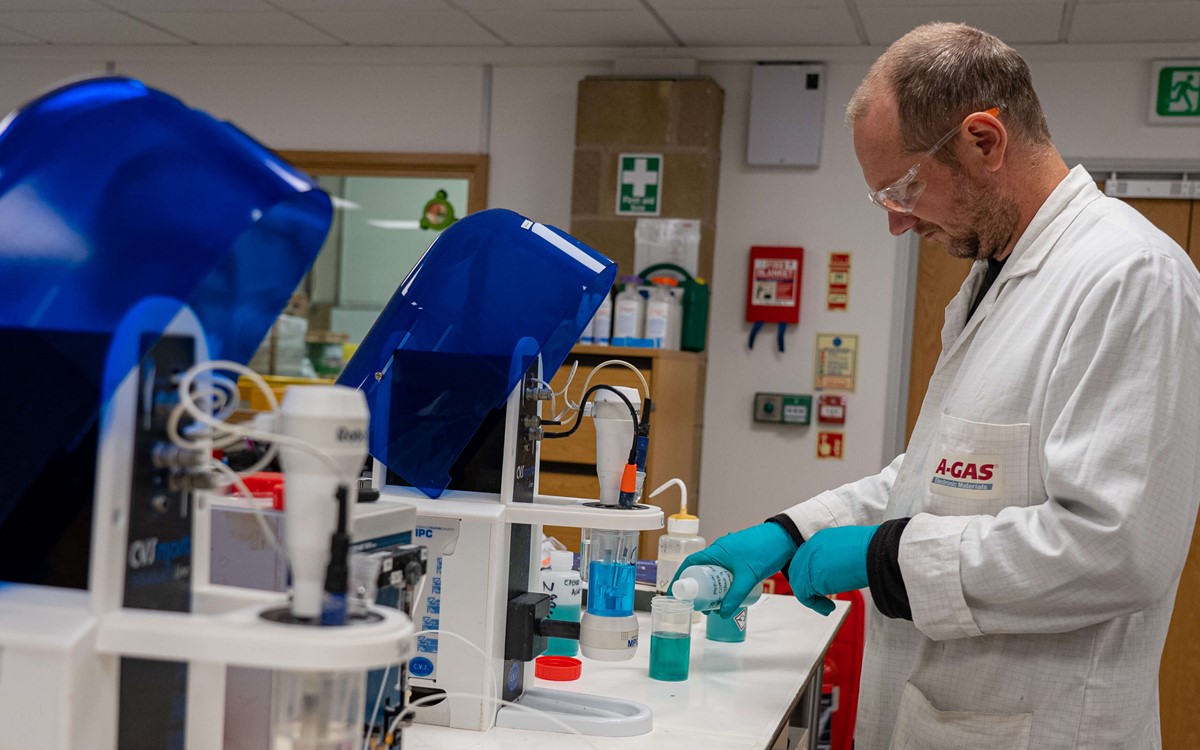 Man pours blue liquid into a plastic container