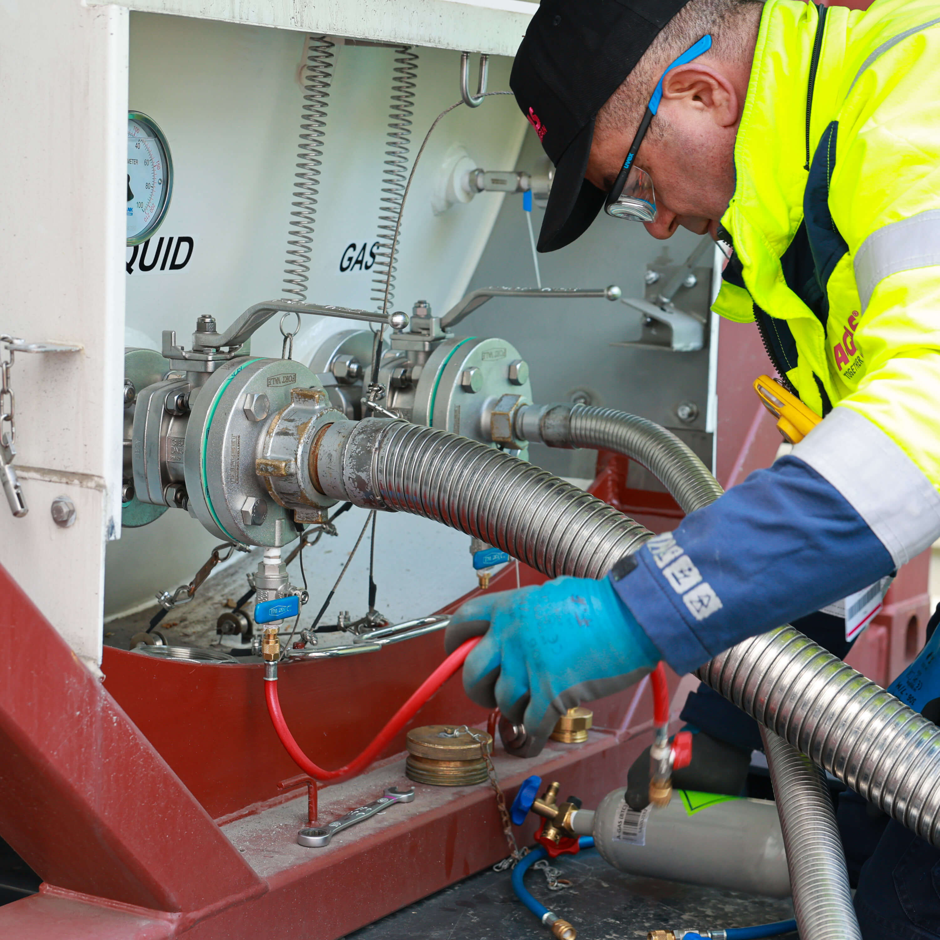 Man in high-vis yellow jacket working with large metal hosing 