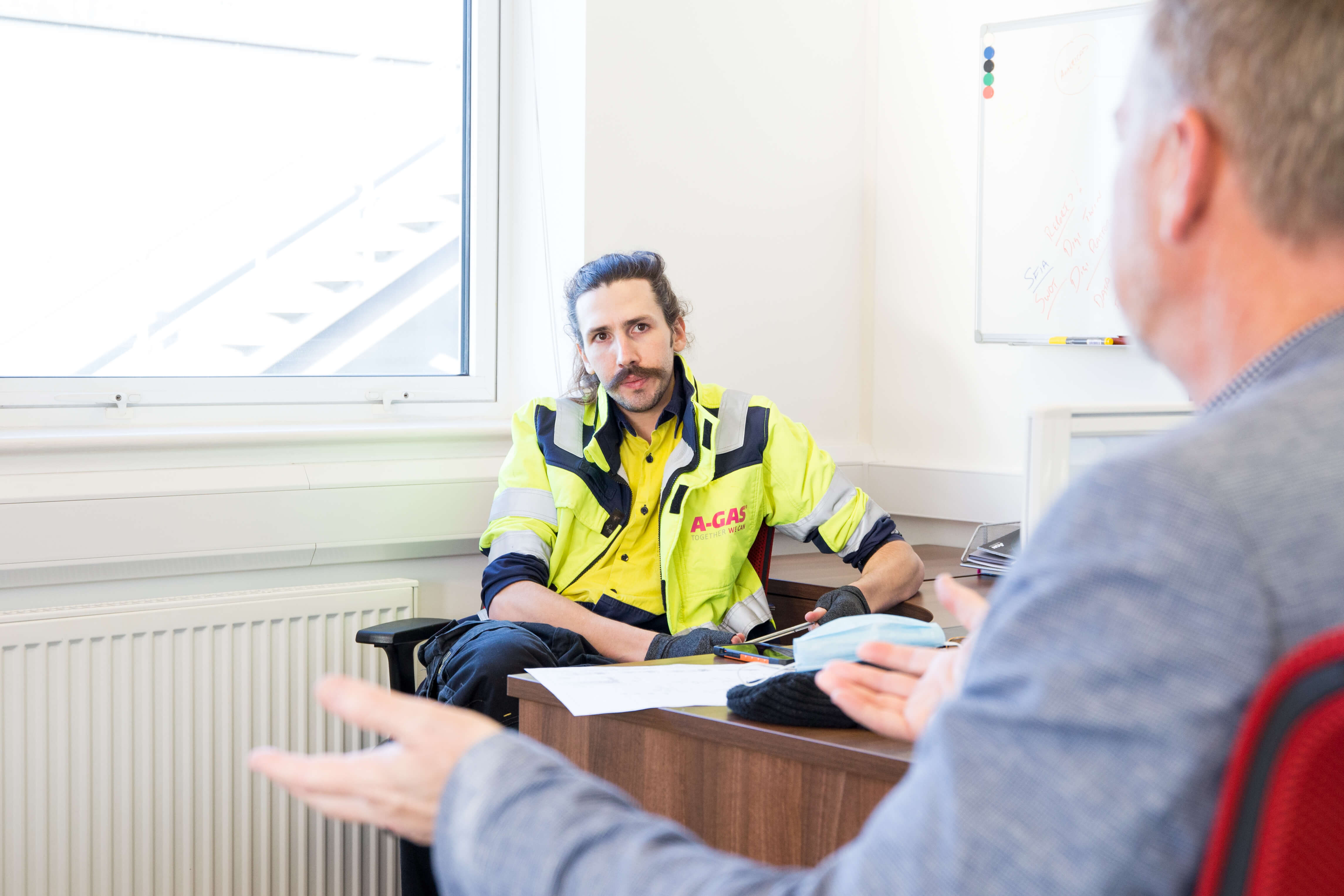 Two men sat opposite each other at a desk talking
