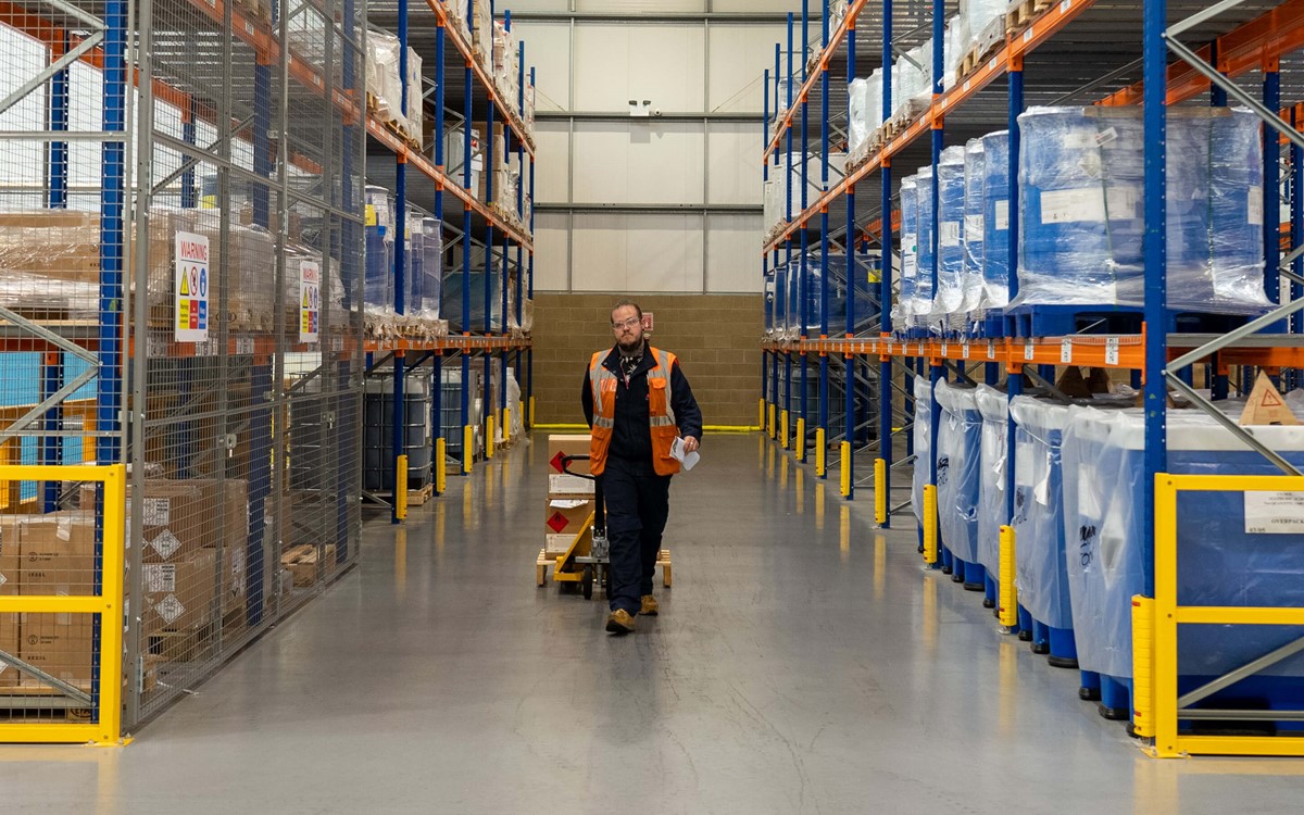 Man pulling a pallet of cardboard boxes in a warehouse