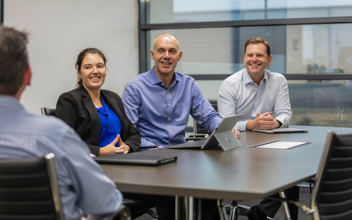 A woman and two men laughing at a meeting