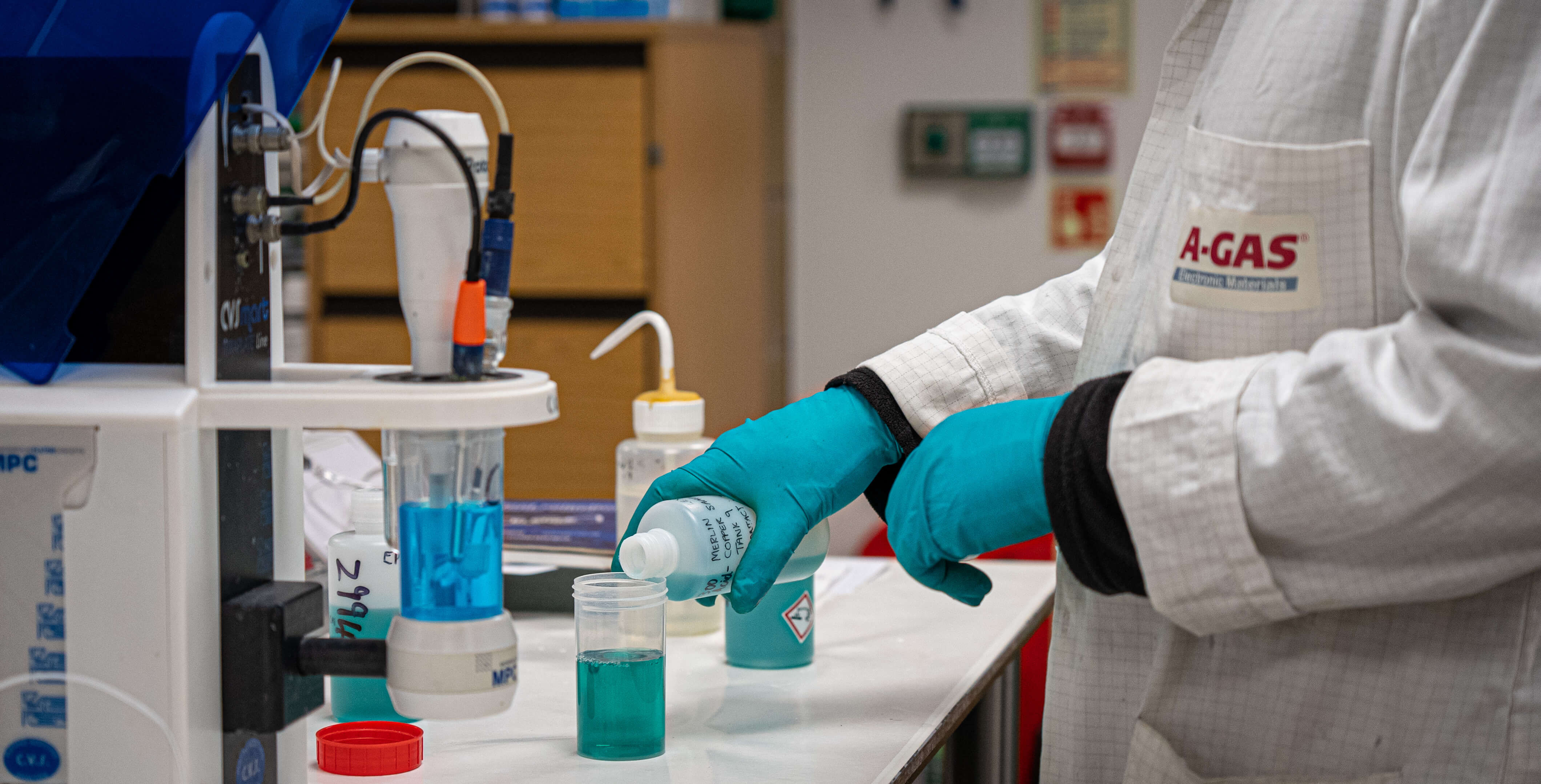 Man pours green liquid into plastic container from the side in laboratory