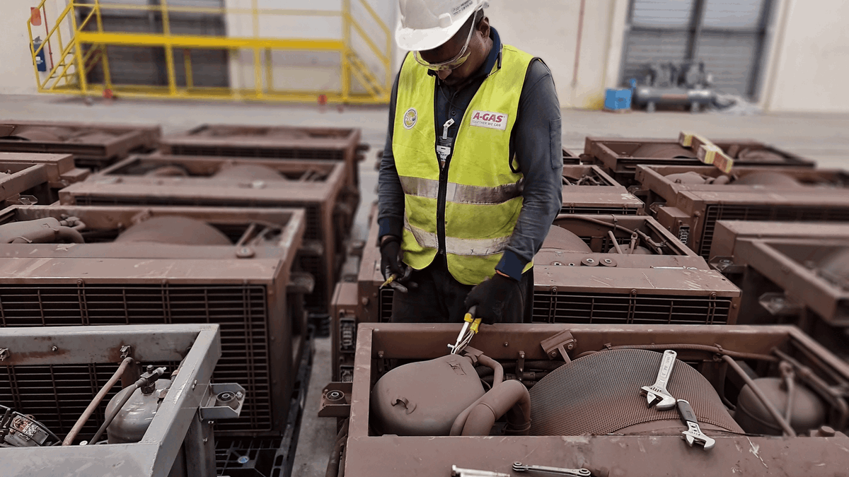A man in a yellow high-vis jacket and hard hat working on an air conditioning unit