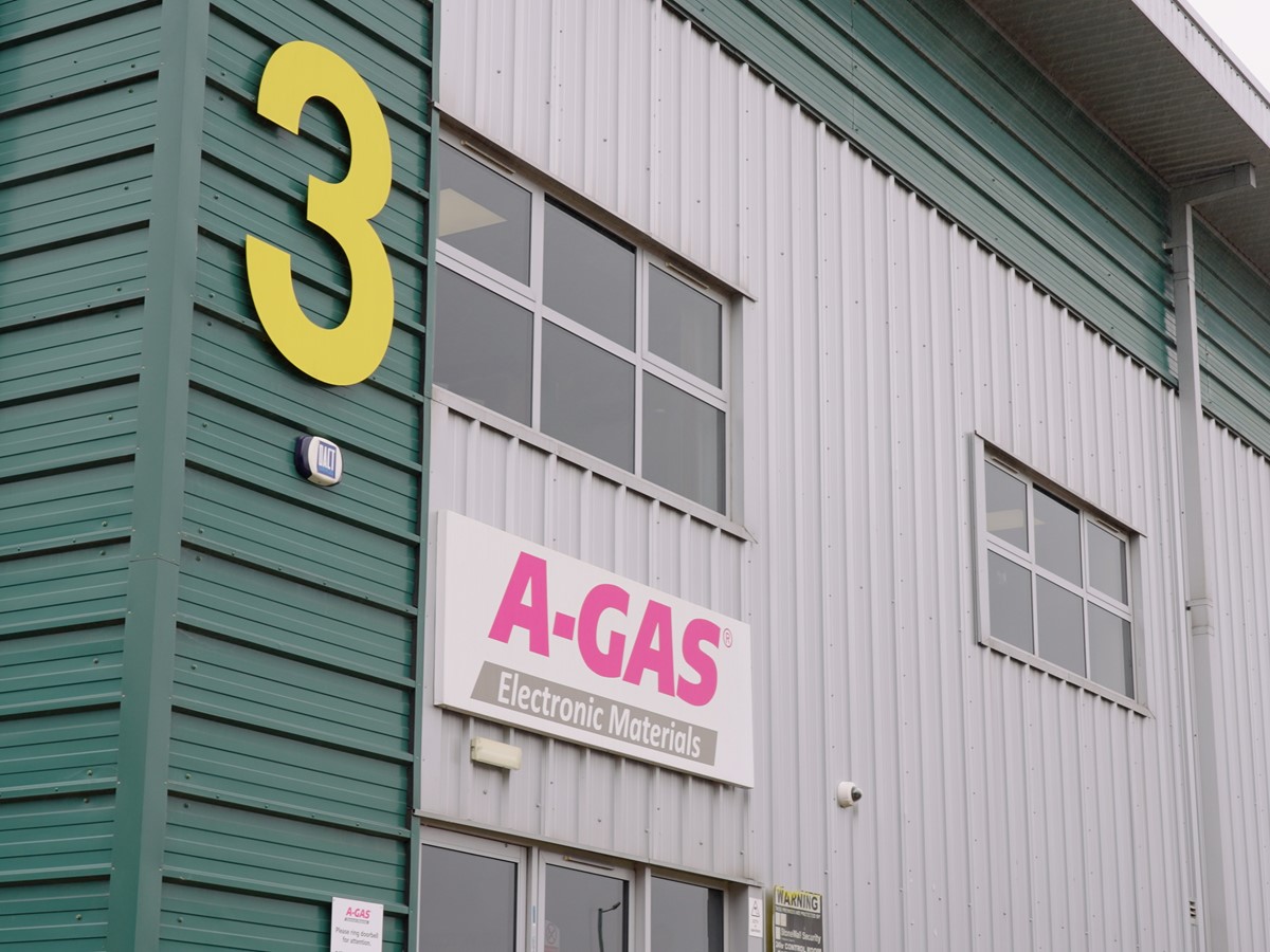 Outside of a grey and green building with pink A-Gas logo above door