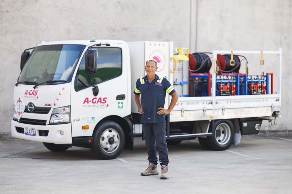 Man standing in front of a white truck with hands on hips while looking at the camera