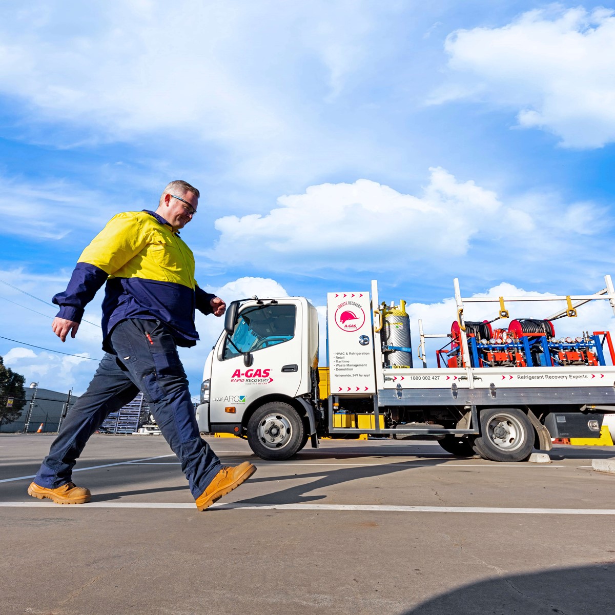 Man walking across a carpark in front of a white A-Gas recovery truck with equipment on the back
