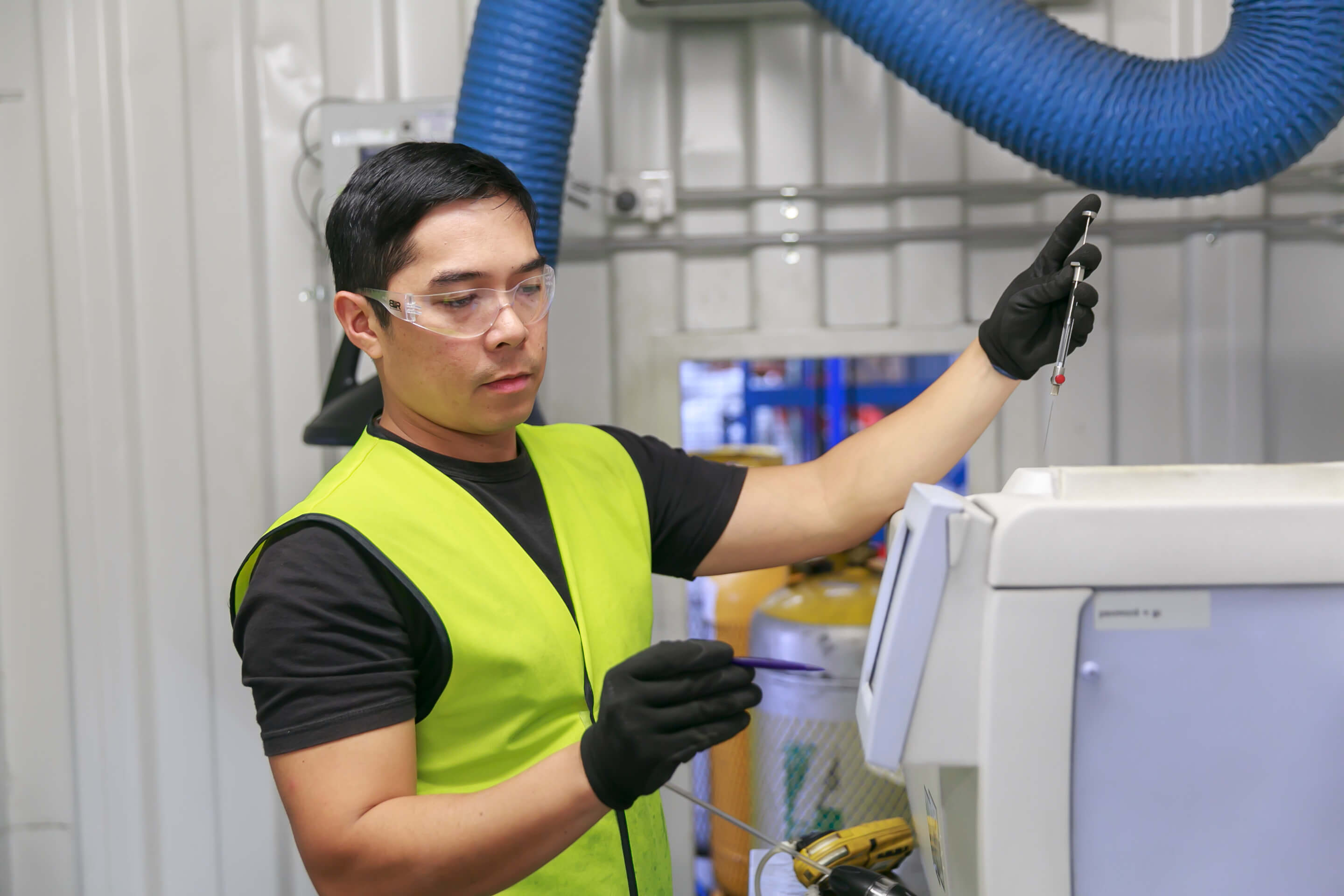 Worker carrying out laboratory analysis on refrigerant gas
