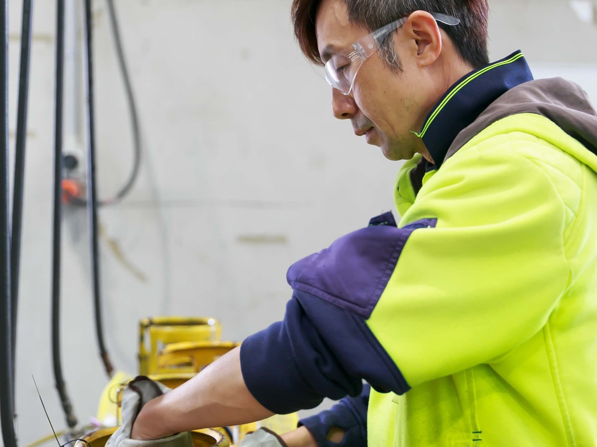 A close up of a warehouse worker, working on a recovery cylinder