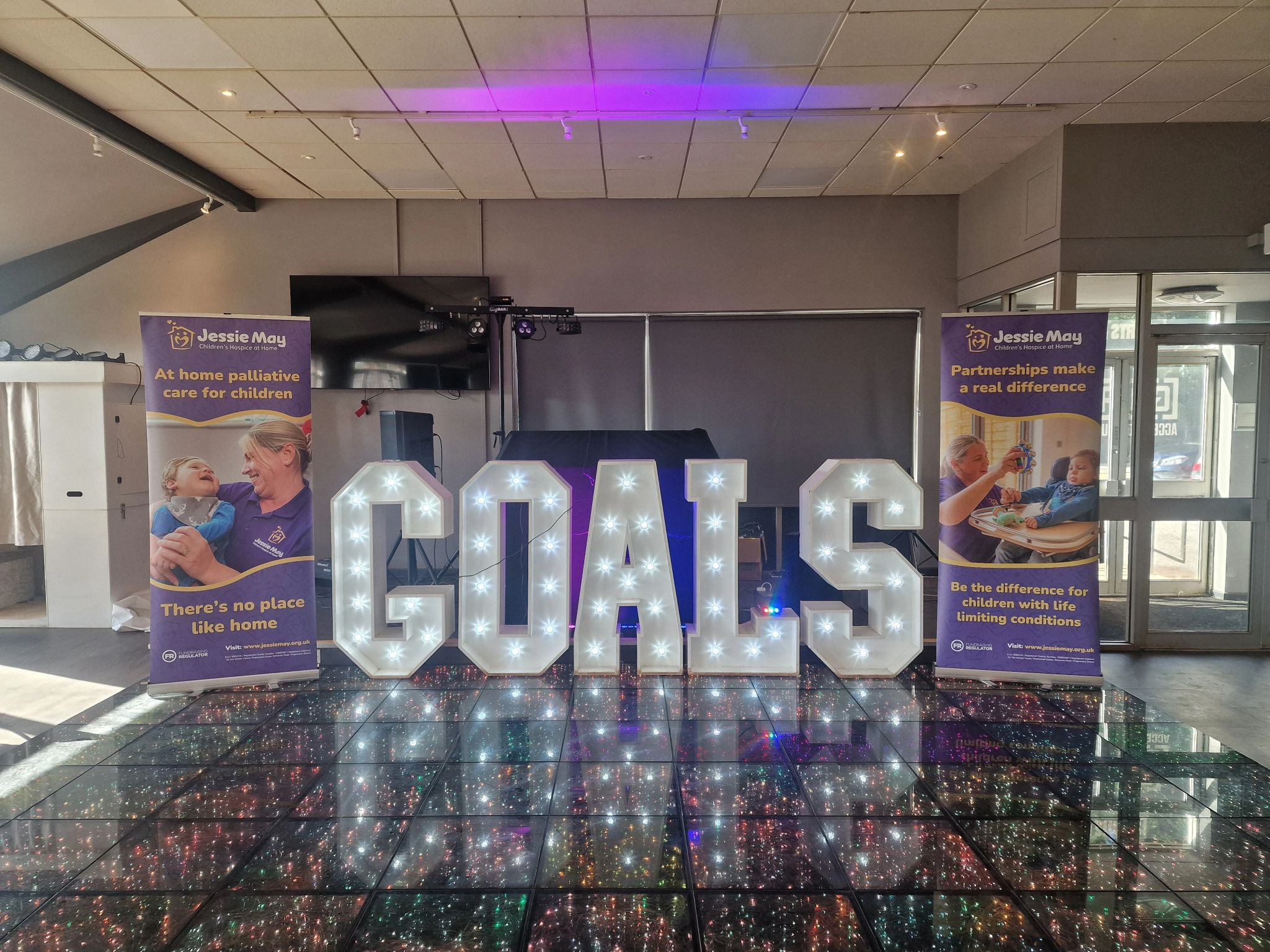 A three dimensional "Goals" logo between two purple banners on a stage 