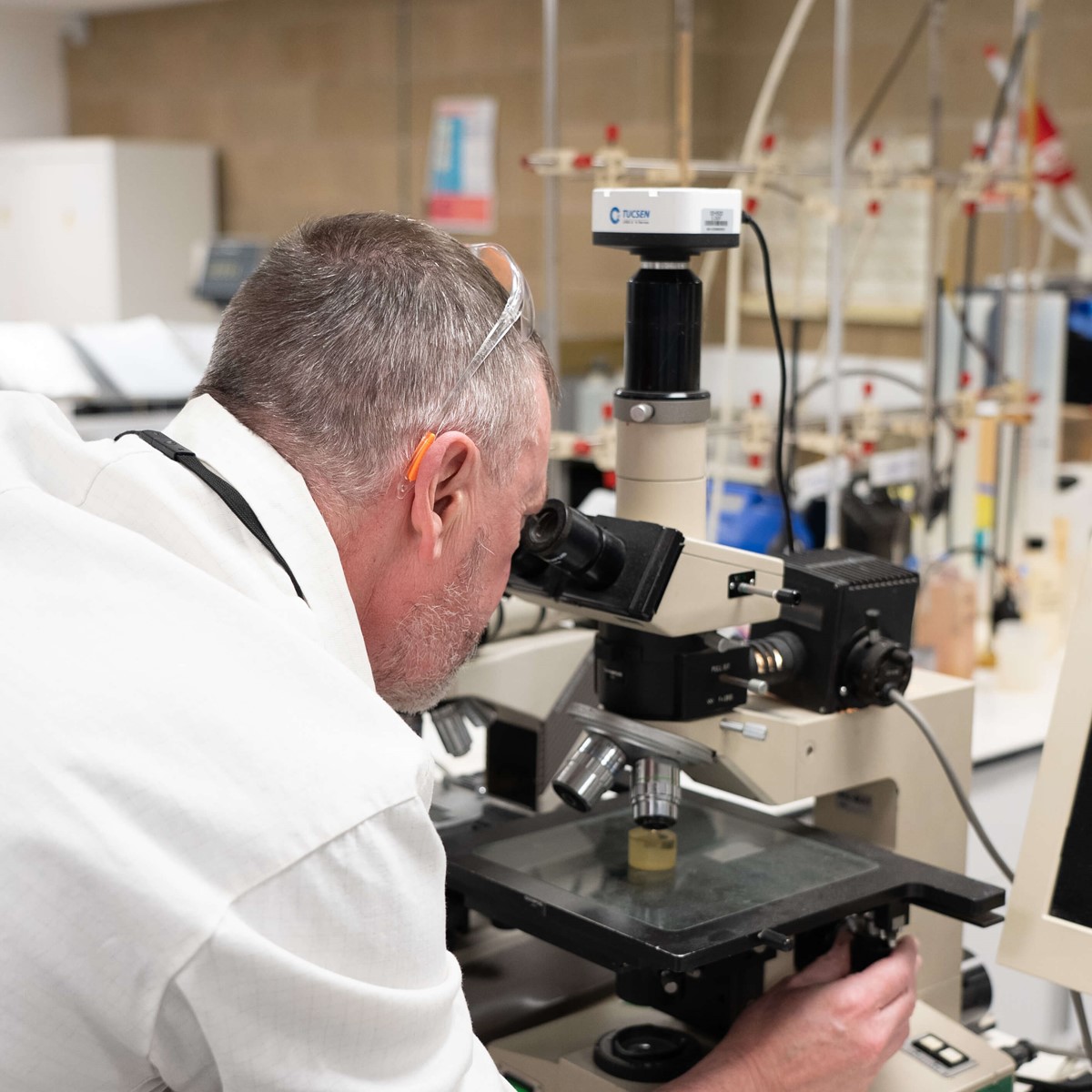 Man looking through a microscope while altering it