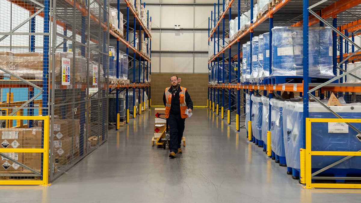 Man pulling a pallet of cardboard boxes in a warehouse